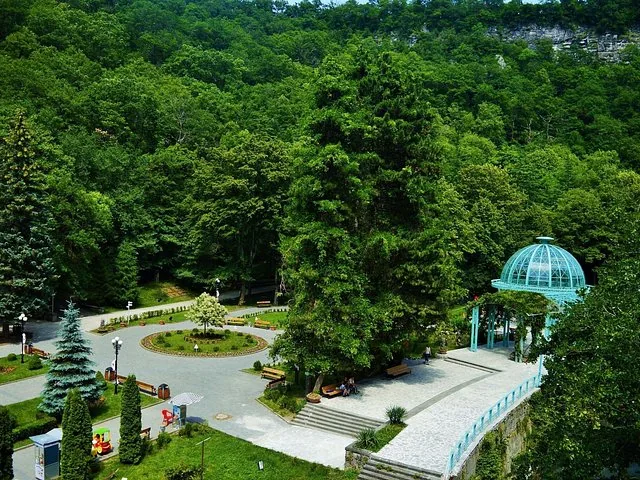 Lush green trees and the glass pavilion in Borjomi Central Park from above
