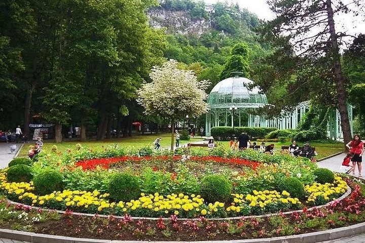 Colorful circular flower bed in Borjomi Central Park with the glass pavilion behind