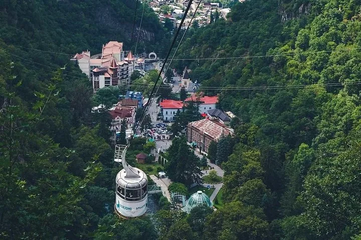 Cable car ascending over Borjomi Central Park surrounded by lush green mountains